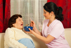 Nurse giving soup to elderly woman